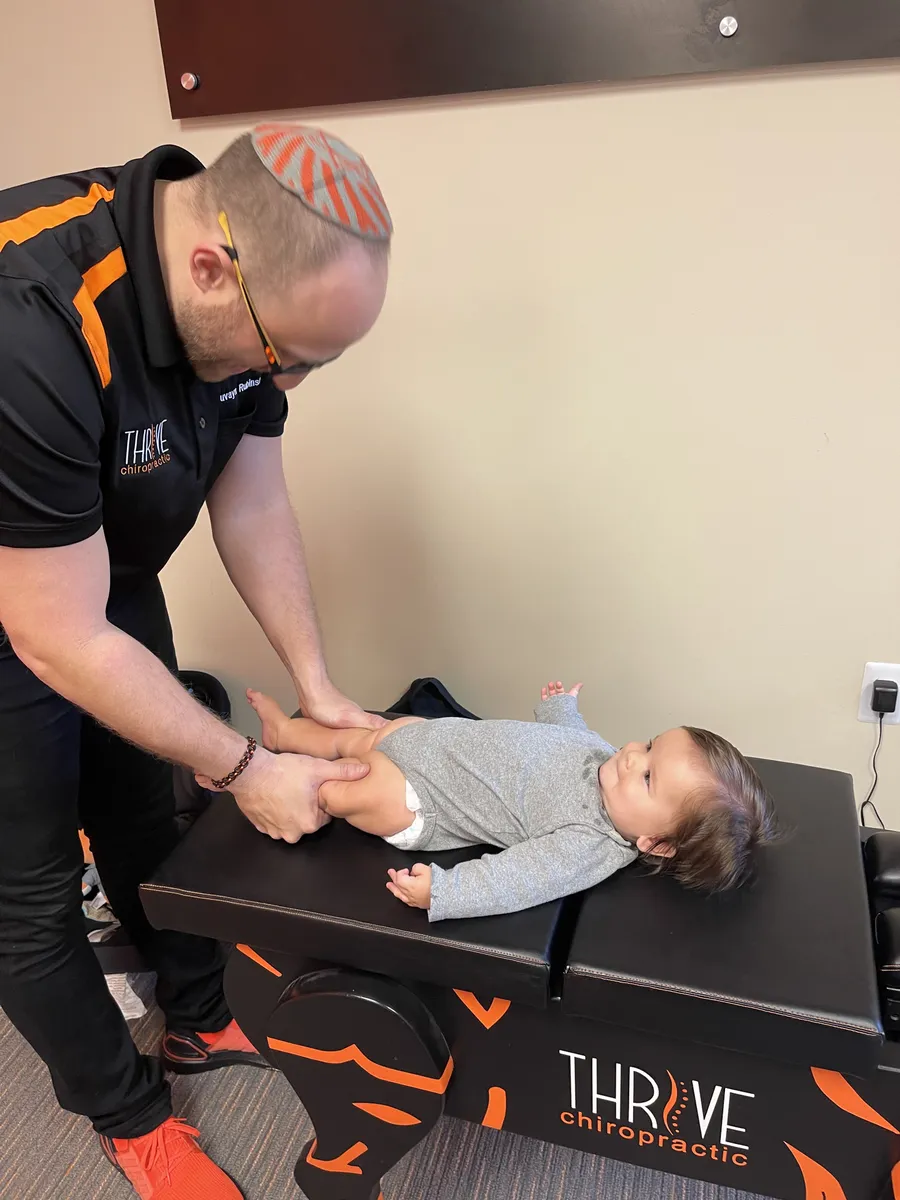 Dr. Rubinstein gently adjusting a baby on the Thrive Chiropractic table.