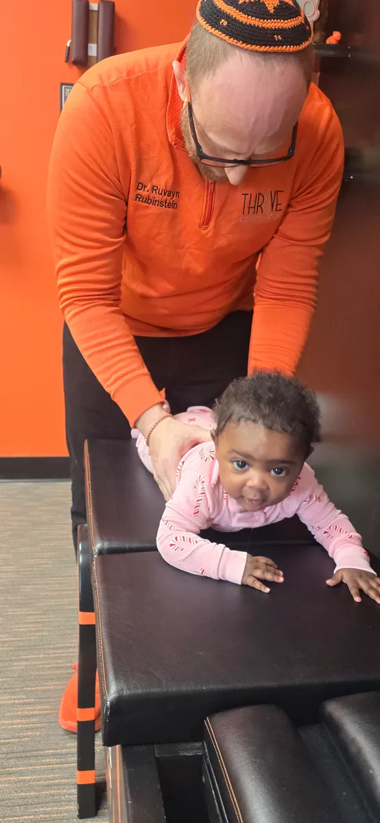A smiling baby during a gentle chiropractic adjustment with Dr. Rubinstein.