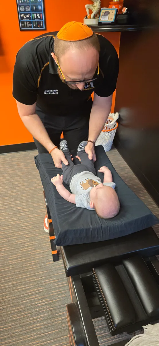 Dr. Rubinstein adjusting a baby lying on the Thrive Chiropractic table.